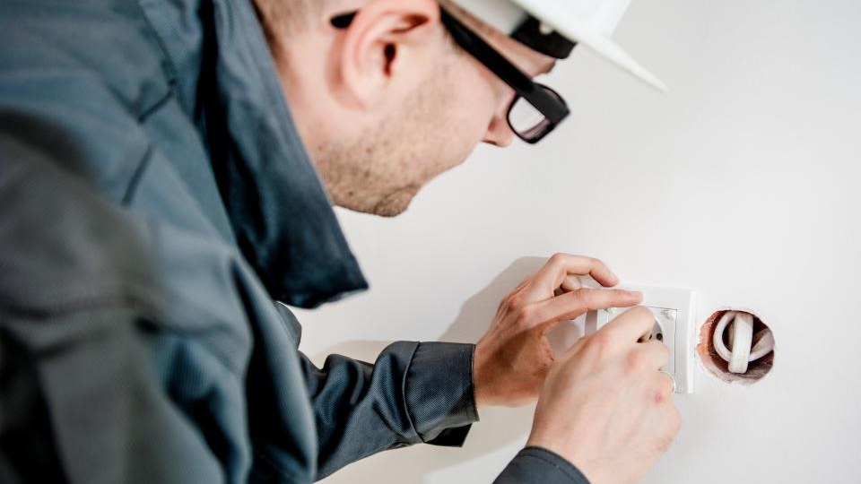 Elektriker montiert eine Steckdose in einer frisch verputzten Wand