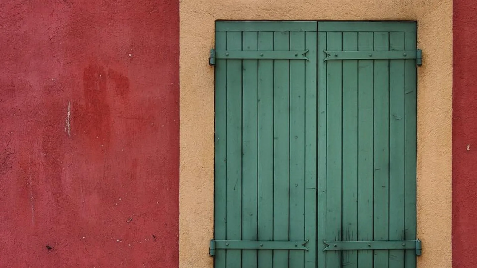 Grüne Fensterläden an einer roten Hauswand