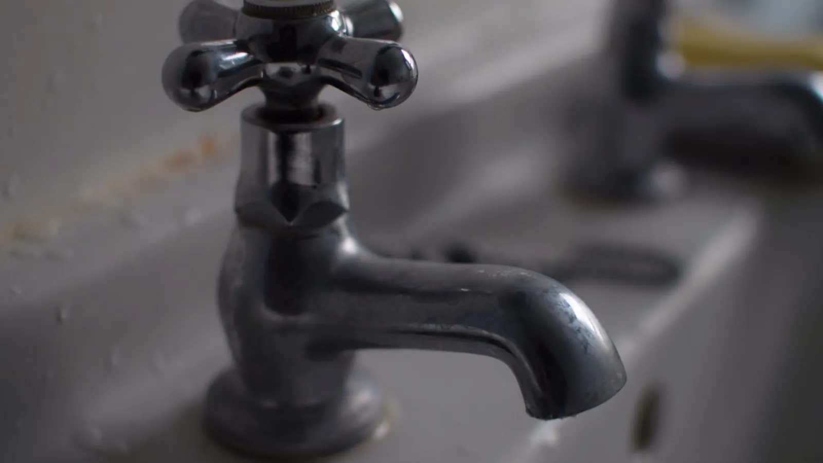 Metallener Wasserhahn in Nahaufnahme vor unscharfem grauem Hintergrund