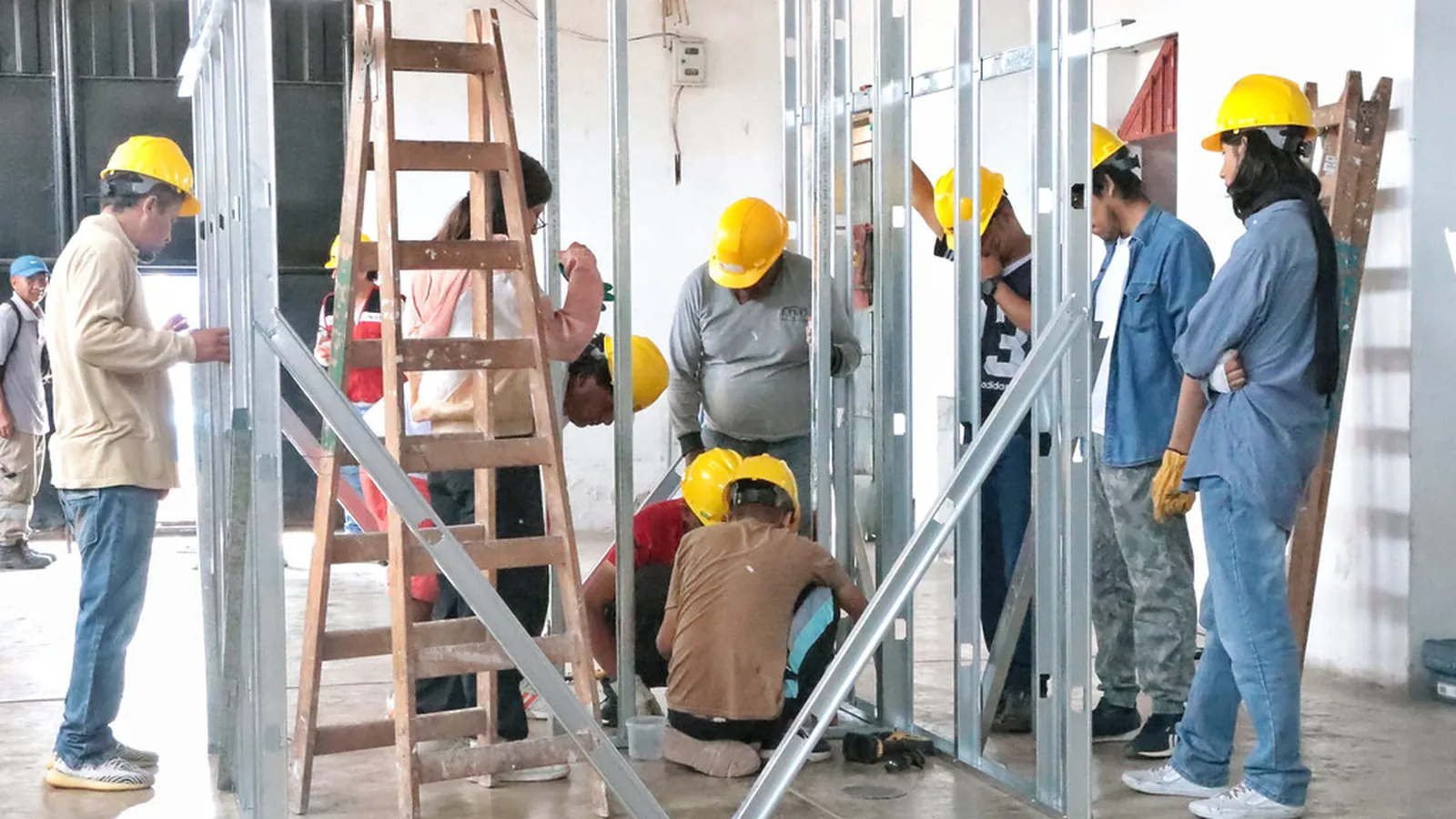 Mehrere Personen montieren ein Metallständerwerk für eine Trockenbauwand