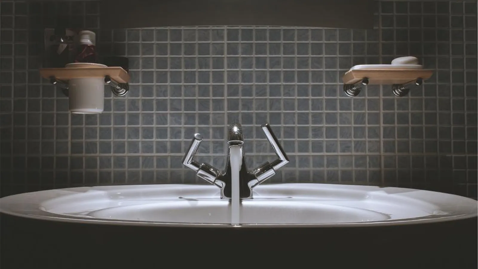 Waschbecken mit Armatur vor dunkler Wandfliesen im Badezimmer