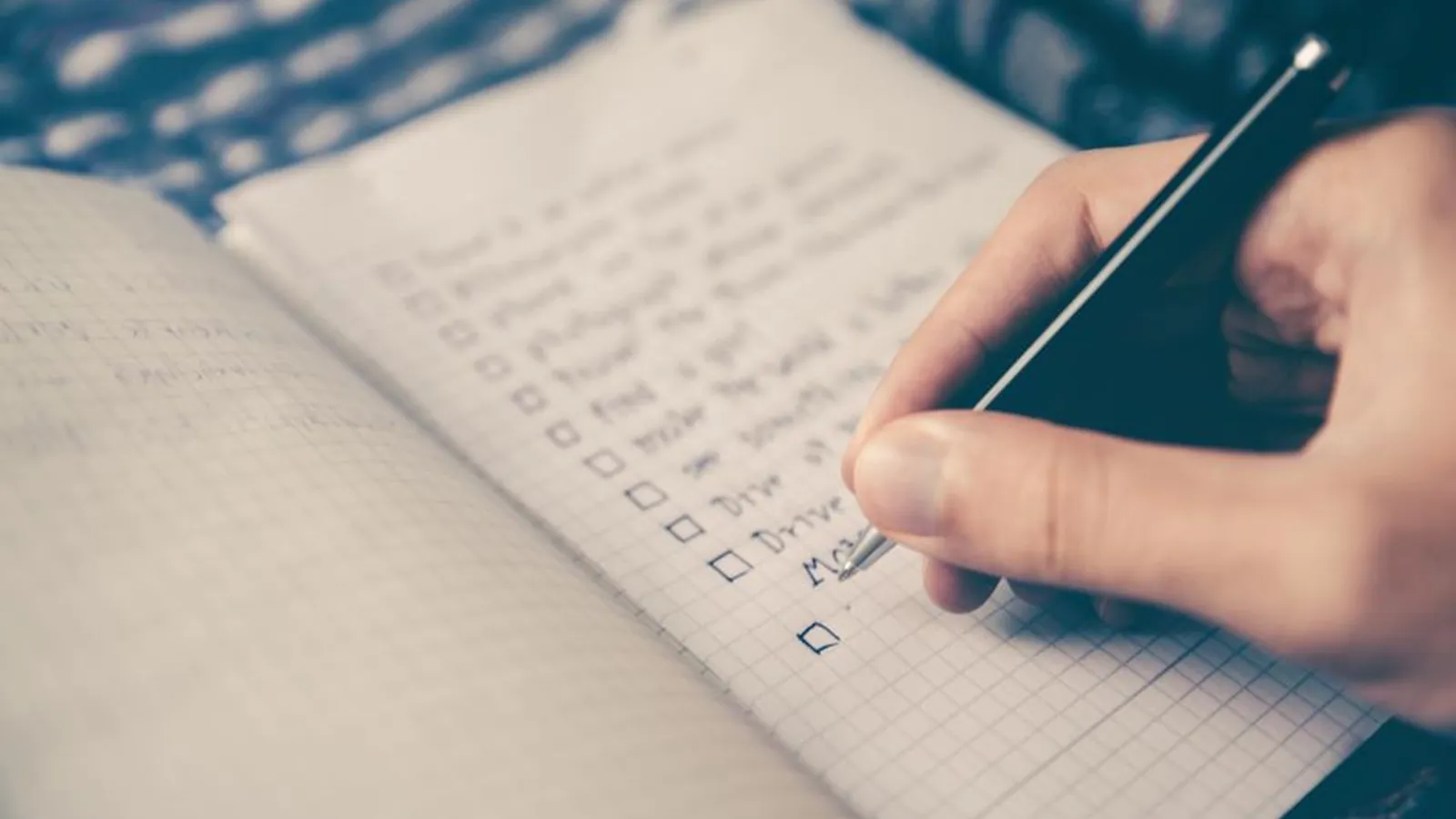 Hand hakt Punkte auf einer handschriftlichen Checkliste in einem Notizbuch ab