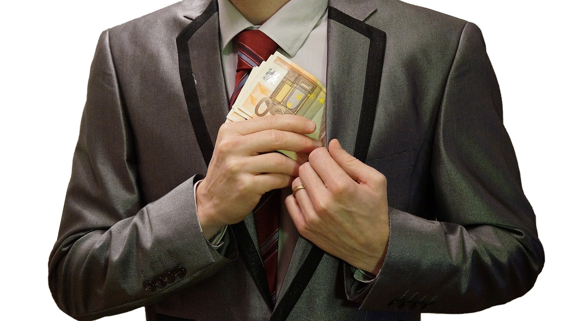 Mann im Anzug steckt ein Bündel Euro-Banknoten in die Innentasche seines Sakkos